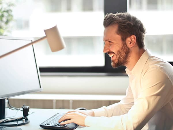 smiling man doing some work on a desktop computer